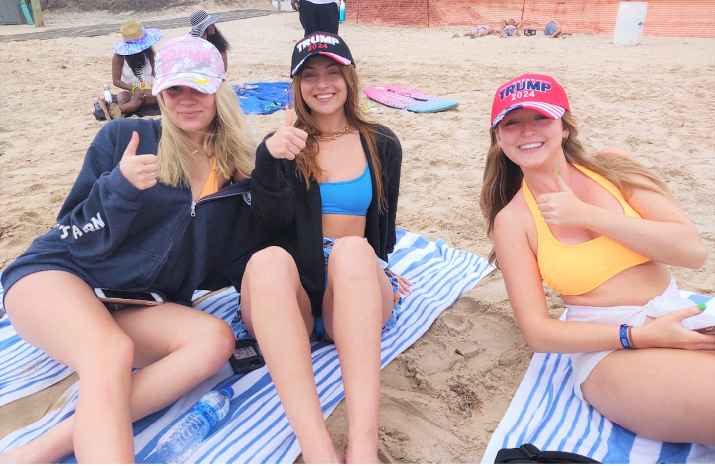 3 beach goers wearing Trump 2024 hats in black, red, and pink camo